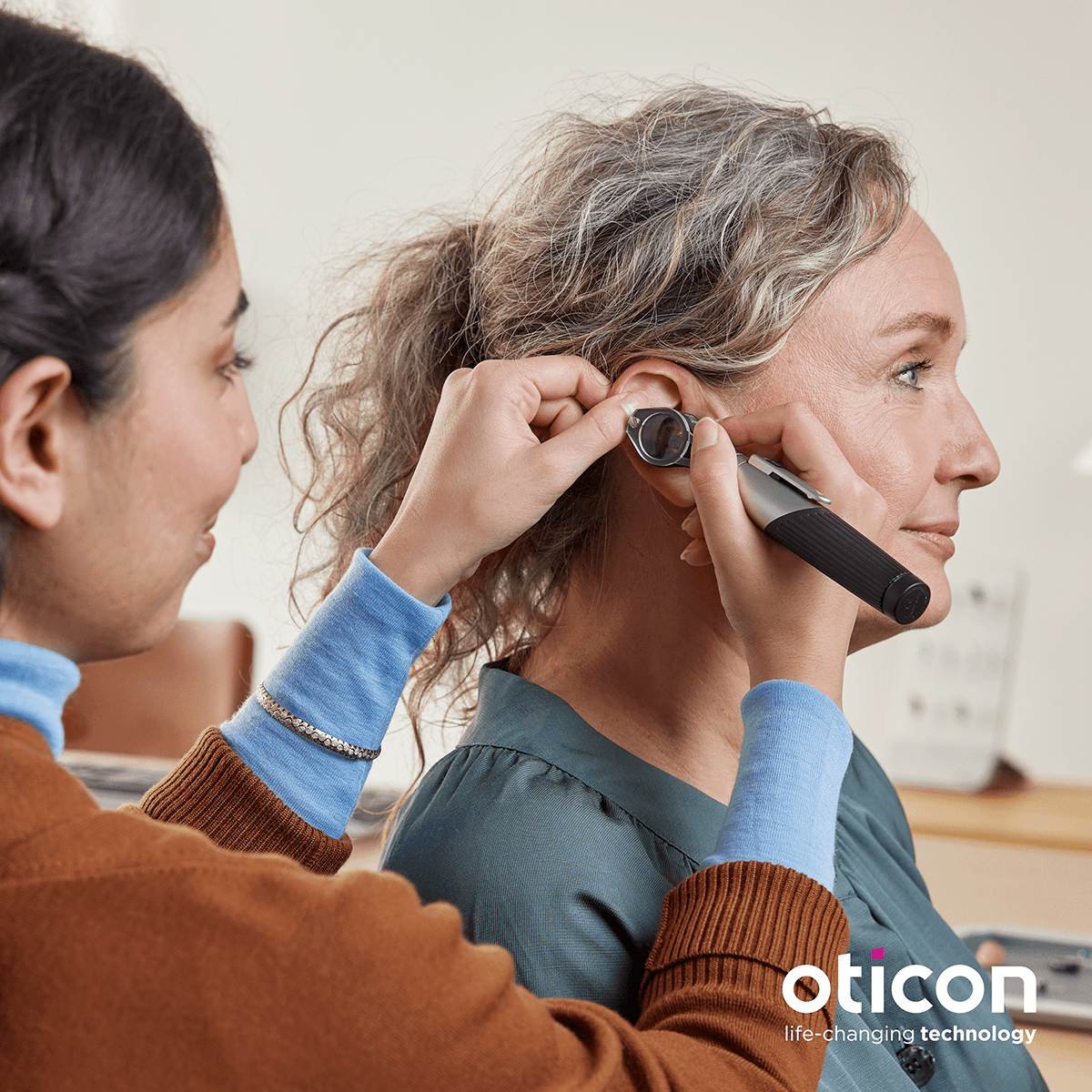 Audioprothésiste examinant l'oreille d'une patiente - Oticon